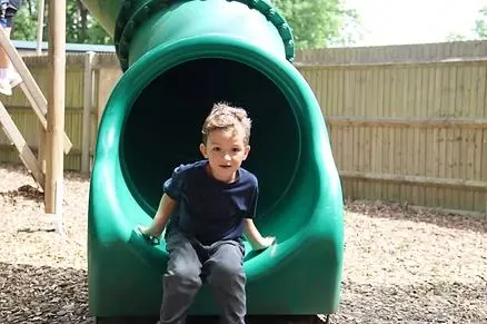 A young boy coming down a tube slide