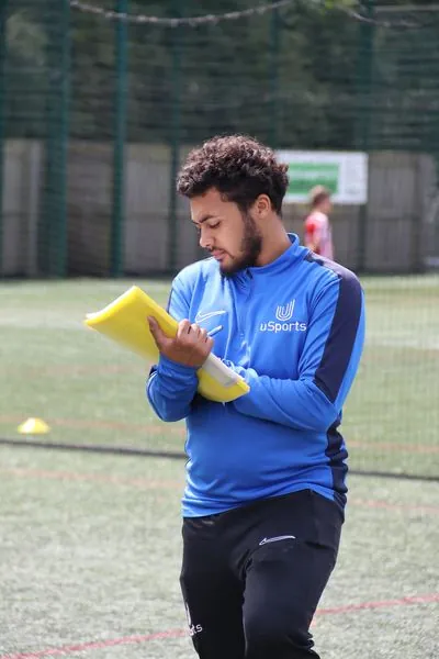 A uSports coach reviewing session plans pitchside