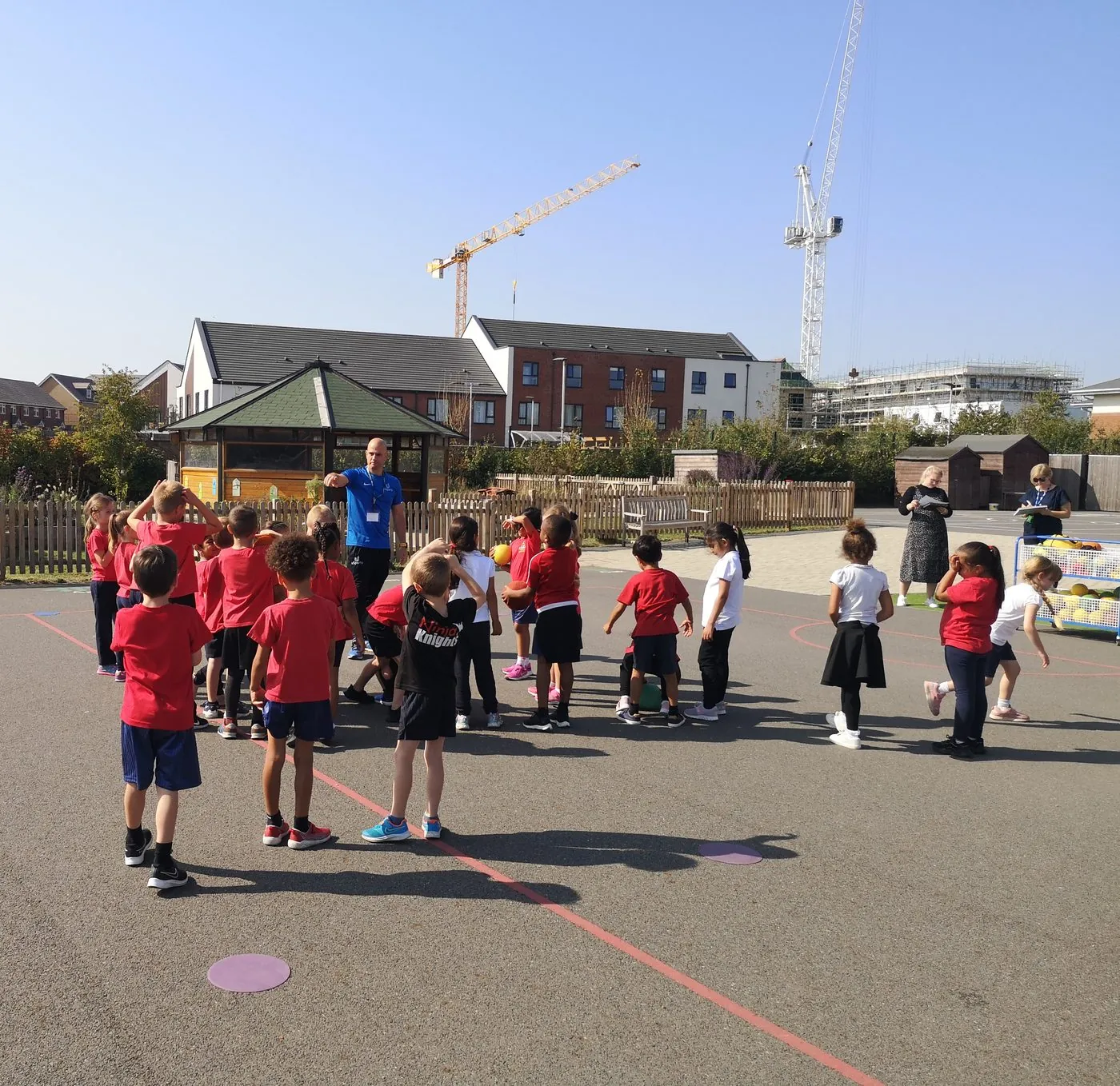 A uSports coach delivering a PE session to a whole class, watched by teachers