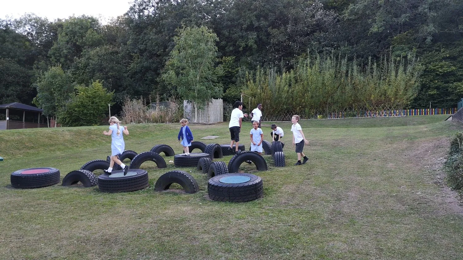 Children playing on a tyre trail in a school field