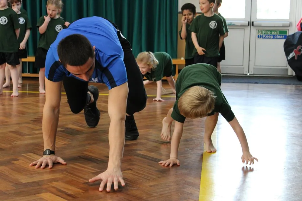 uSports coach leading a bear-crawl exercise with school children
