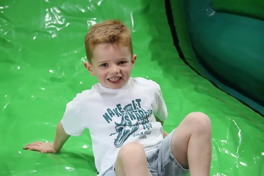 A smiling boy on an inflatable slide at a holiday camp