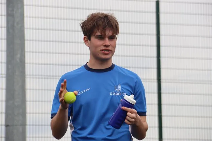 A uSports coach with a tennis ball during a session
