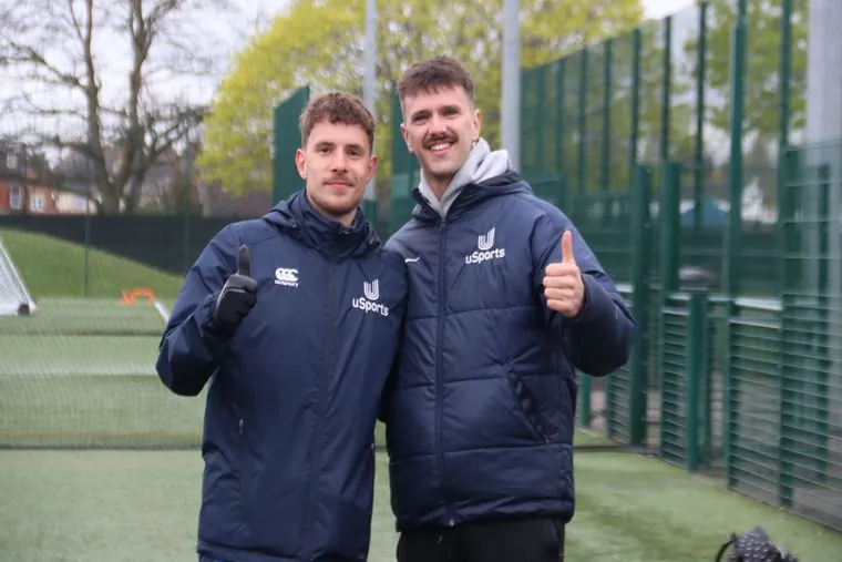 Two uSports coaches giving a thumbs up on a 3G pitch