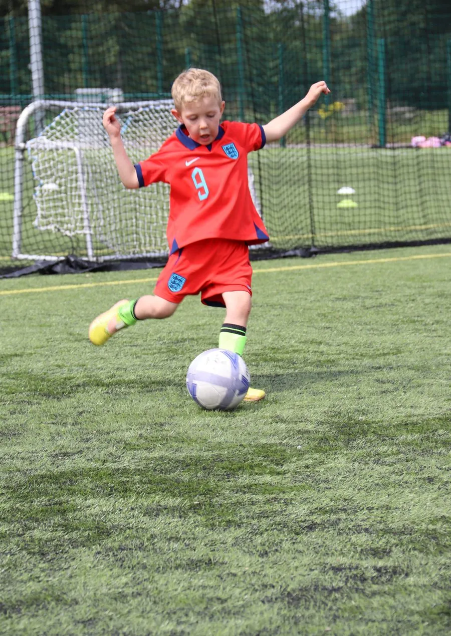 A young player striking a ball at a uSports football session