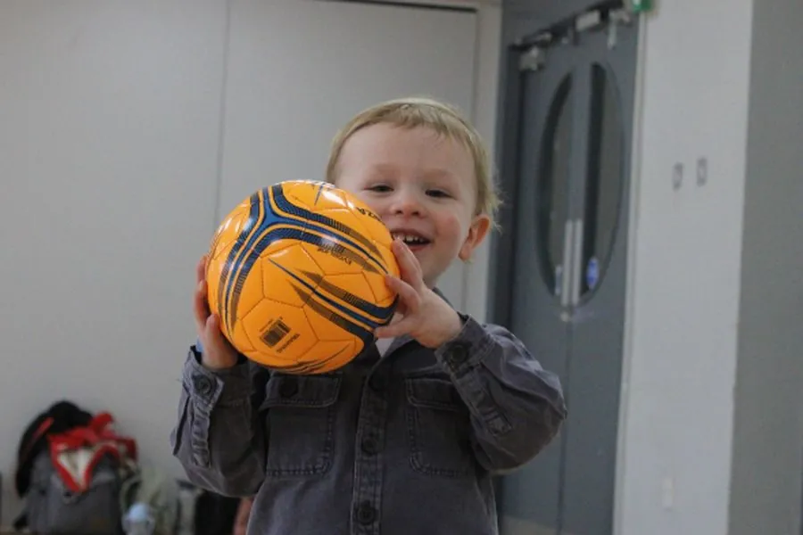 Toddler holding a football at a uSports toddler football class