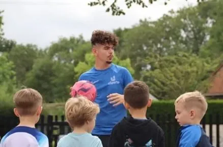 A uSports coach talking to a group of children