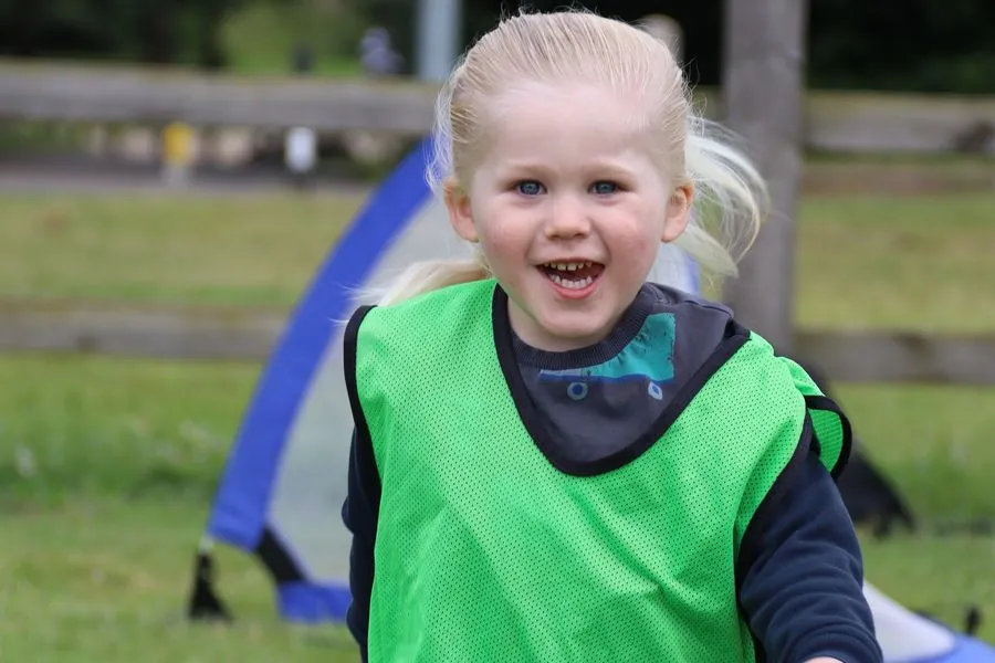 Young child in a bib running at a uSports infant football development centre
