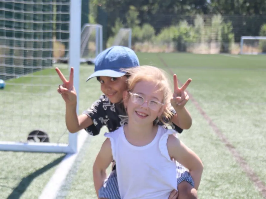 Two children, one giving the other a piggyback, at a uSports holiday camp