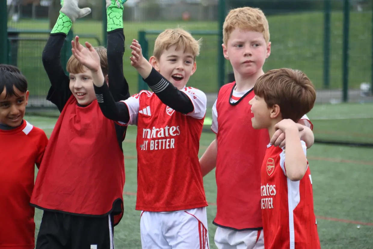 A group of children in football kit celebrating together at a uSports session