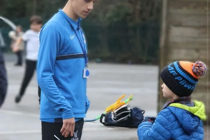 A uSports coach talking with a child in the playground